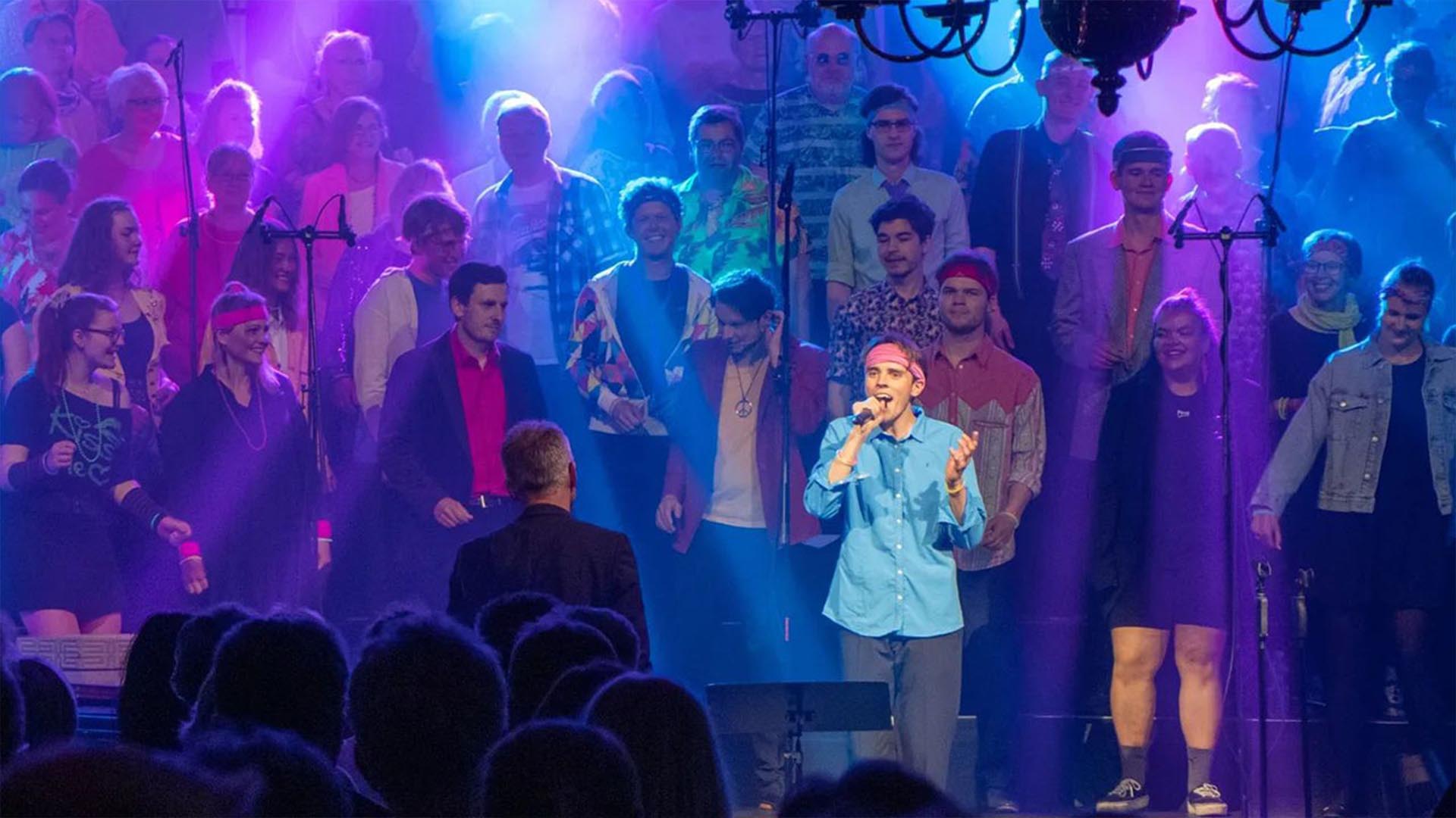 Ein Ausschnitt aus einer HDR-Veranstaltung mit einem Sänger vor einem Chor, im Hintergrund eine Lichtshow